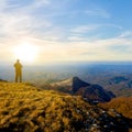 hiker silhouette stay on mount top and looking far at the sunset