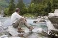 Hiker sitting at a mountain creek Royalty Free Stock Photo