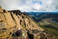 Hiker sitting on a rocky mountaintop overlooking the scenic landscape. Cradle Mountain, Australia.