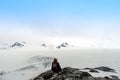 Hiker sitting at the summit of a mountain overlooking the Harding Ice Field in Alaska enjoying the spectacular and surreal view