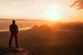 Hiker stand on the sharp corner of sandstone rock in rock empires park and watching over the misty and foggy morning valley to Sun