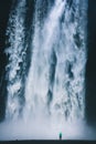 Hiker standing in front of gigantic Skogafoss waterfall in Iceland