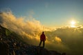 A Person Standing on the Mountain with Clouds During Sunset/Sunr