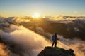 A Person Standing on the Mountain with Clouds During Sunset/Sunr