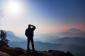 Hiker is standing on the peak of rock in rock empires park and watching over the misty and foggy morning valley to Sun