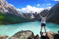 Hiker standing with raised hands near the beautiful mountain lake and enjoying valley view Royalty Free Stock Photo