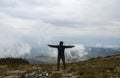 The hiker standing with raised hands on a top of mountain and enjoying the view of cloudy valley Royalty Free Stock Photo