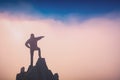 Hiker standing on a rocky cliff and points to the sky Royalty Free Stock Photo