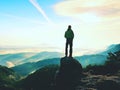 Hiker is standing on sandstone peak in rocky park and watching over misty and foggy morning valle Royalty Free Stock Photo