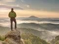 Hiker is standing on sandstone peak in rocky park and watching over misty and foggy morning valle Royalty Free Stock Photo