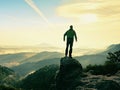 Hiker is standing on sandstone peak in rocky park and watching over misty and foggy morning valle Royalty Free Stock Photo