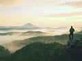 Hiker is standing on sandstone peak in rocky park and watching over misty and foggy morning valle Royalty Free Stock Photo