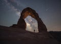 Hiker standing under Delicate Arch and the Night Sky Royalty Free Stock Photo