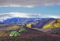 Hiker stands near a tent and enjoying the summer sunrise