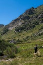 Hiker strolls past a green mountain. Rila mountain range, Bulgaria.