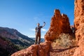 Hiker taking a selfie on a cliff edge in Southern Utah near hoodoo formations of red rock