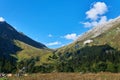 Hiker camp in autumn meadow in front of a mountain pass