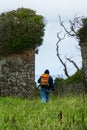Hiker at threshold between isolated ruins of medieval Carrigaholt Castle, Ireland, and panoramic view beyond the tower wall.
