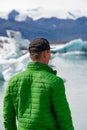 Hiker tourist looking at view Iceberg landscape with giant icebergs and lake. Arctic nature heavily affected by climate