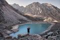 Hiker tourist taking photograph of mountain lake at sunset