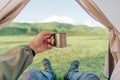 Traveler man resting in a tent with cup of tea and enjoying view of mountain. Royalty Free Stock Photo