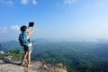 Hiker use digital tablet taking photo at mountain peak cliff Royalty Free Stock Photo