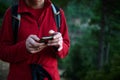 Hiker Using Smartphone on Forest Trail in Red Jacket with Backpack Royalty Free Stock Photo