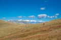 Hiker walking along a path through a field of dried blueberries with the Observatory, the highest peak of the Bjelasnica mountain Royalty Free Stock Photo