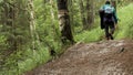 Hiker walking in a forest trail in green summer woods, active lifestyle concept. Stock footage. Rear view of a tourist