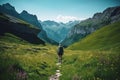 Hiker walking on a green meadow trail against the backdrop of a breathtaking mountain landscape. The image conveys a sense of