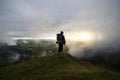 Hiker Watching over Hills in the Clouds as the Sun Sets Royalty Free Stock Photo