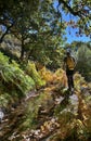 Hiker walking next to the ditch Almiar in an autumn forest of the Alpujarra and yellow and green ferns