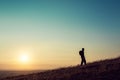 A hiker walking up hill, silhouetted against the setting sun Royalty Free Stock Photo