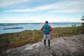 Hiker wearing a jacket and carrying a backpack, standing on a rock watching Lake Jatkonjarvi at sunset in Koli National Park, Royalty Free Stock Photo