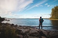 Hiker wearing a jacket and carrying a backpack walks along the beach and watches Lake Jatkonjarvi at sunset in Koli National Park Royalty Free Stock Photo