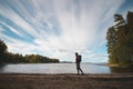Hiker wearing a jacket and carrying a backpack walks along the beach and watches Lake Jatkonjarvi at sunset in Koli National Park Royalty Free Stock Photo