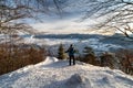 Hiker wih trekking poles and backpack looking from top of the hill on winter snowy landscape. Hill Cebrat over town Ruzomberok,