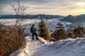 Hiker wih trekking poles and backpack looking from top of the hill on winter snowy landscape. Hill Cebrat over town Ruzomberok,
