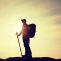 Hiker in windcheater, baseball cap and with trekking poles stand on mountain peak rock. Royalty Free Stock Photo