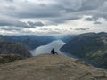 Hiker woman admiring view on fjord Lysefjord from Preikestolen massive cliff, famous Norway viewpoint. Moody autumn day