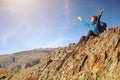 Hiker woman with backpack sitting on rock of a mountain and enjoying sunrise