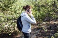 Hiker woman with backpack walking on path in autumn forest. Female speaks on the mobile phone during rest Royalty Free Stock Photo