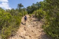 Hiker woman climbing a path through the Massis de les Cadiretes`.