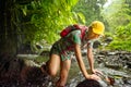 Hiker woman in hiking overcomes river in rainforest.