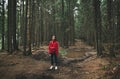 Hiker woman in a red raincoat stands in the forest on a mountain path on a puddle background with a swamp and looks camera.Hiking Royalty Free Stock Photo