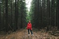 Hiker woman in a red raincoat stands on a trail in the mountains,looks in camera, girl on a mountain hike. Full length photo of