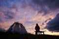 Hiker woman sitting on a bench near tent at sunset Royalty Free Stock Photo