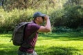 Man explorer in the forest, scanning the horizon with binoculars