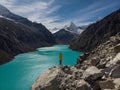 Hiker in yellow jacket at blue turquoise alpine mountain lake Laguna Paron in Caraz Huaraz Ancash Cordillera Blanca Peru