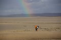 Hikers admiring the landscape and a rainbow on top of them in Normandy, France.